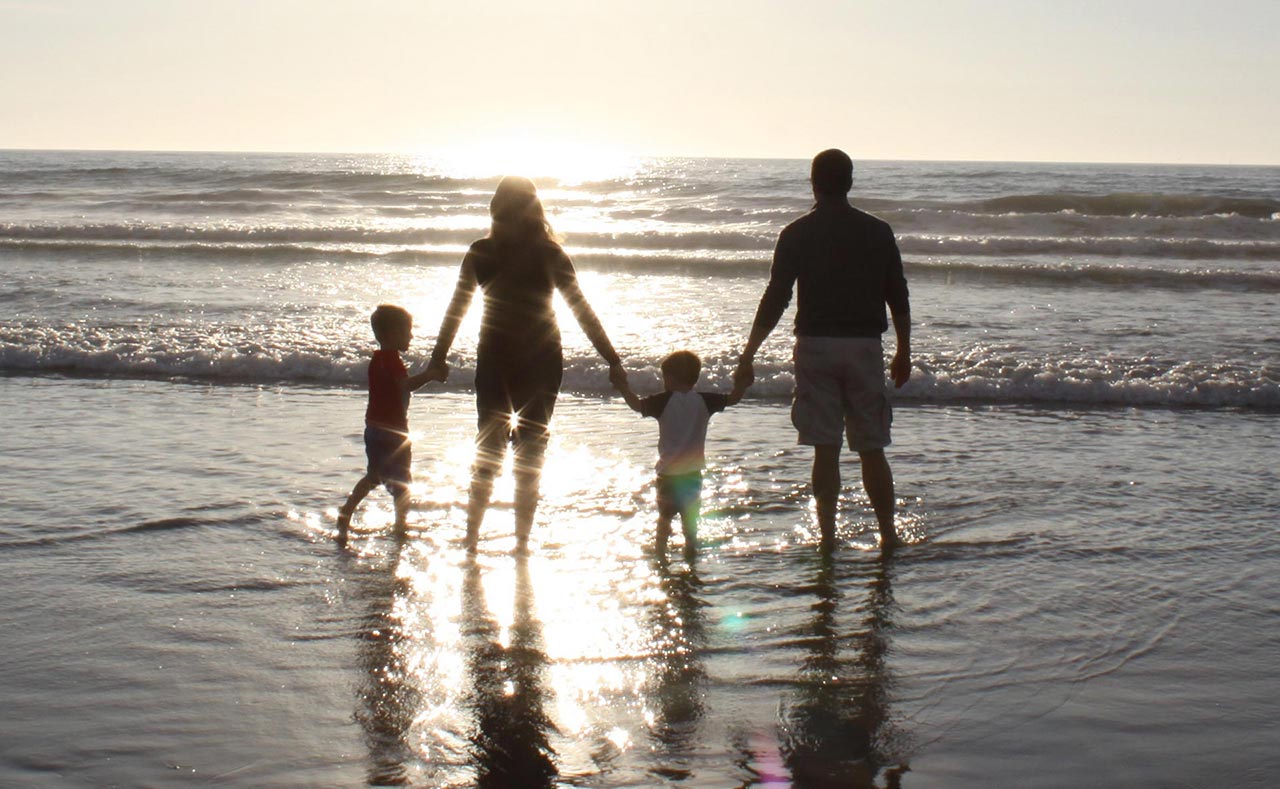 family-holding-hands-on-beach-at-dusk